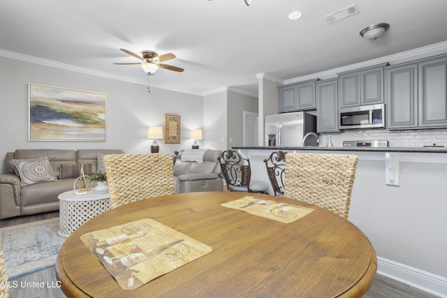 dining area with sink, crown molding, wood-type flooring, and ceiling fan