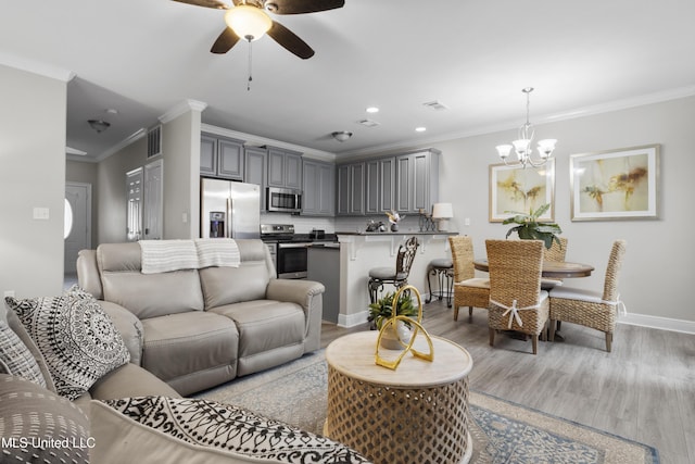 living room featuring crown molding, ceiling fan with notable chandelier, and light hardwood / wood-style floors