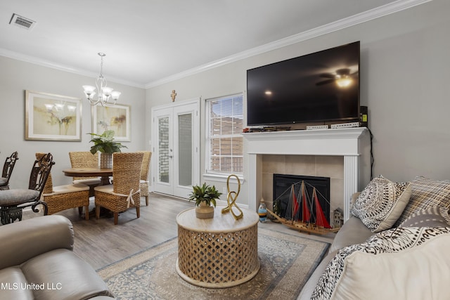 living room with crown molding, an inviting chandelier, a fireplace, and hardwood / wood-style floors