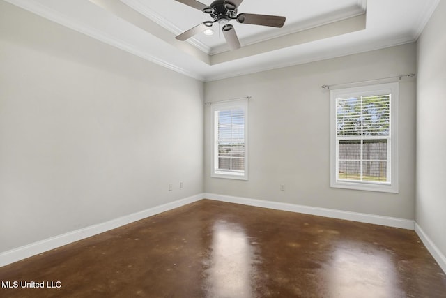 spare room featuring concrete floors, crown molding, a tray ceiling, plenty of natural light, and baseboards