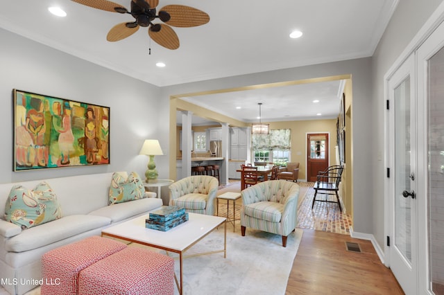 living room with crown molding, light hardwood / wood-style floors, and ceiling fan