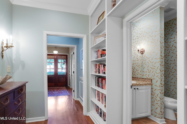 hallway with ornamental molding, light wood-type flooring, and built in shelves