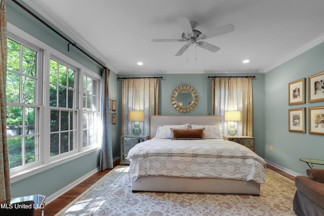 bedroom featuring hardwood / wood-style flooring, ceiling fan, ornamental molding, and multiple windows