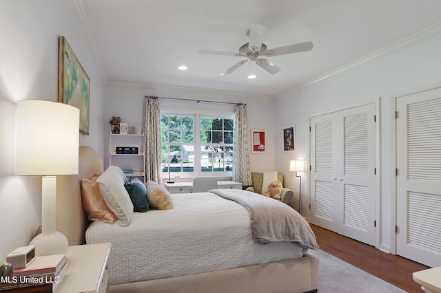 bedroom featuring crown molding, ceiling fan, hardwood / wood-style floors, and two closets