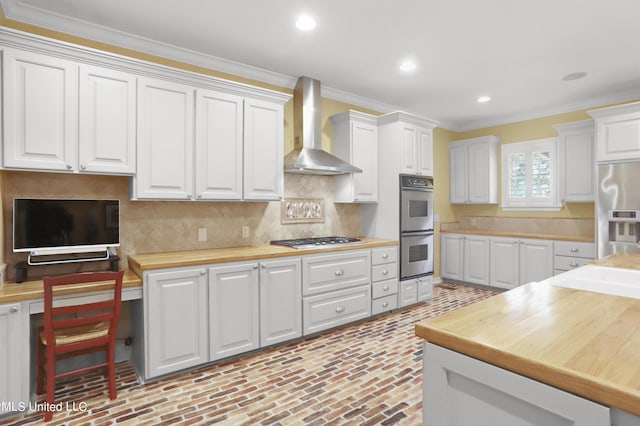 kitchen with stainless steel appliances, white cabinetry, and wall chimney range hood