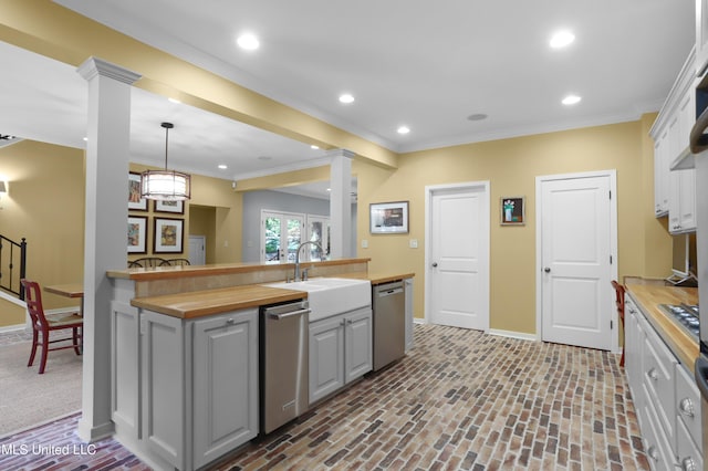 kitchen with hanging light fixtures, appliances with stainless steel finishes, butcher block counters, and decorative columns