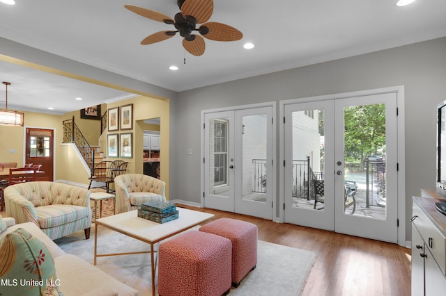 living room with ornamental molding, french doors, ceiling fan, and light wood-type flooring