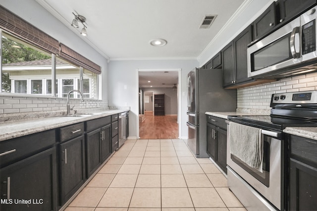 3306 Nottingham Rd, Ocean Springs, MS 39564 - kitchen featuring stainless steel appliances, dark cabinets, backsplash, light tile patterned floors, and crown molding