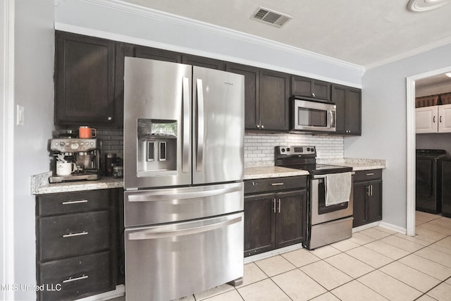 3306 Nottingham Rd, Ocean Springs, MS 39564 - kitchen with stainless steel appliances, washer and clothes dryer, decorative backsplash, crown molding, and light tile patterned floors