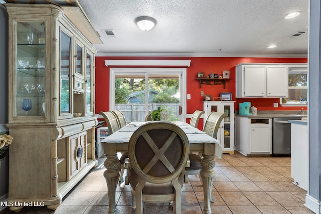 tiled dining space featuring ornamental molding and a textured ceiling