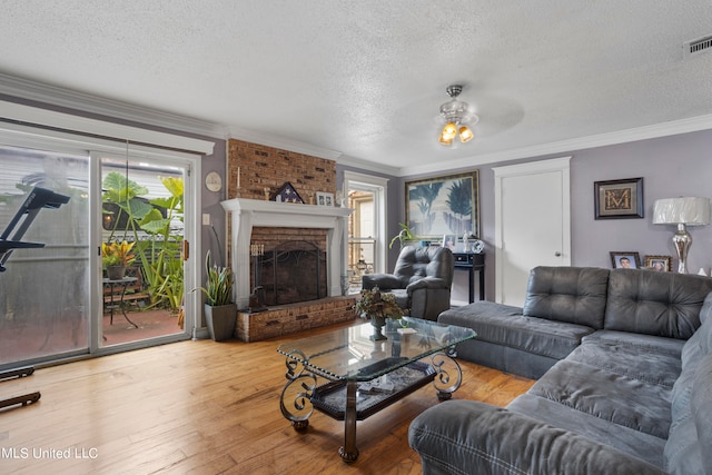 living room featuring a textured ceiling, a brick fireplace, plenty of natural light, and hardwood / wood-style floors