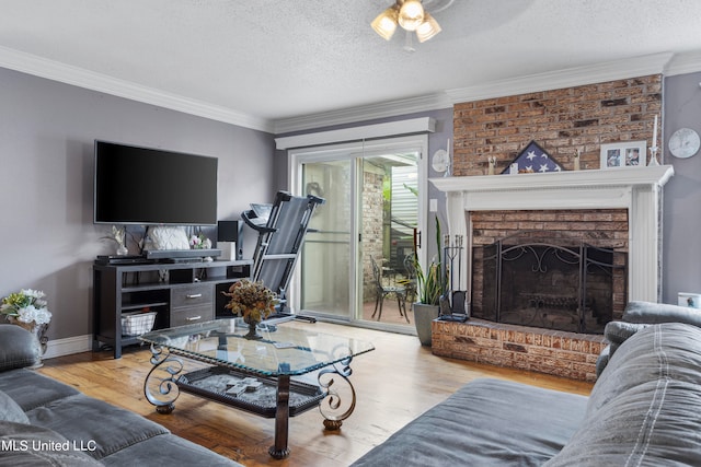 living room featuring crown molding, hardwood / wood-style flooring, a textured ceiling, and a brick fireplace