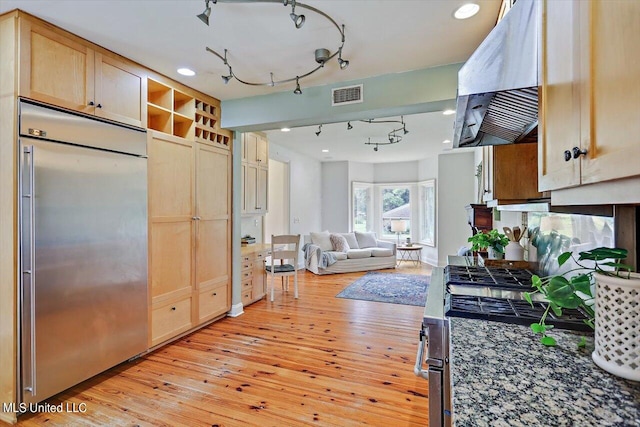 kitchen with stainless steel built in fridge, light hardwood / wood-style flooring, range hood, dark stone countertops, and light brown cabinetry