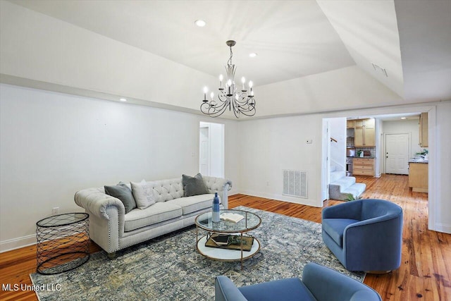 living room with lofted ceiling, a notable chandelier, and wood-type flooring