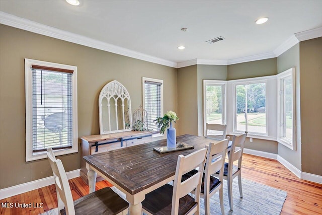 dining room featuring crown molding, light wood-type flooring, and a healthy amount of sunlight