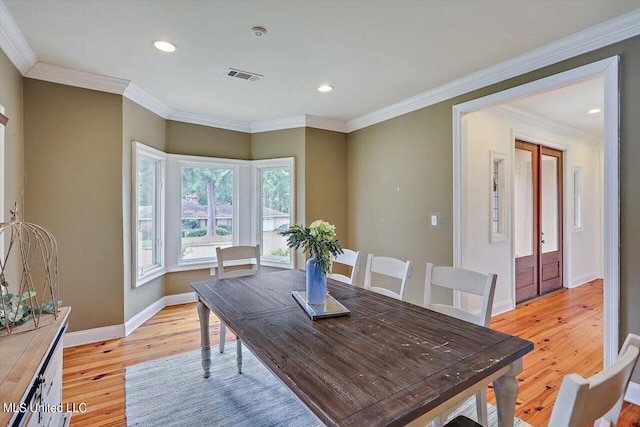 dining room with crown molding and light hardwood / wood-style flooring