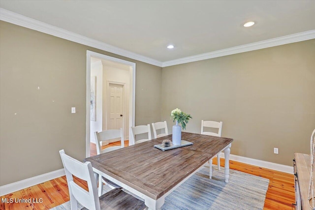 dining space with ornamental molding and light hardwood / wood-style flooring