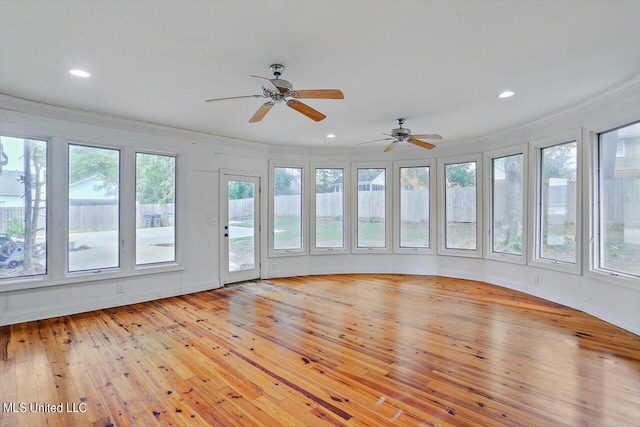 unfurnished sunroom featuring ceiling fan and plenty of natural light