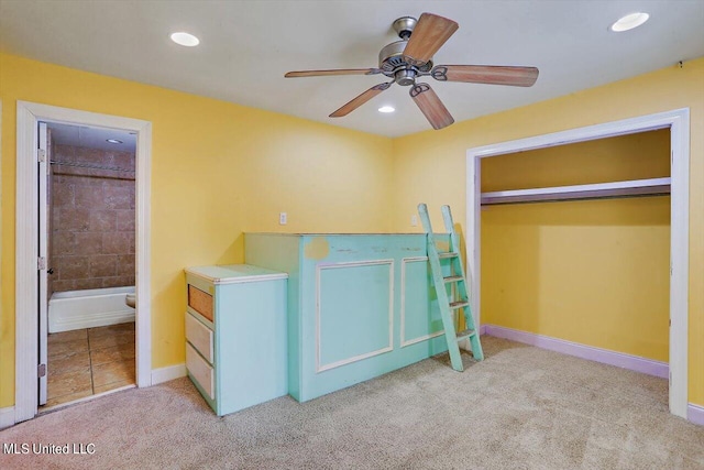 unfurnished bedroom featuring light carpet, ensuite bathroom, a closet, and ceiling fan