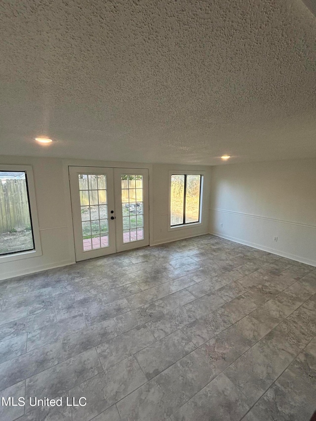 spare room featuring a wealth of natural light, french doors, and a textured ceiling