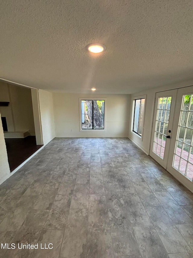 spare room with french doors, a healthy amount of sunlight, and a textured ceiling