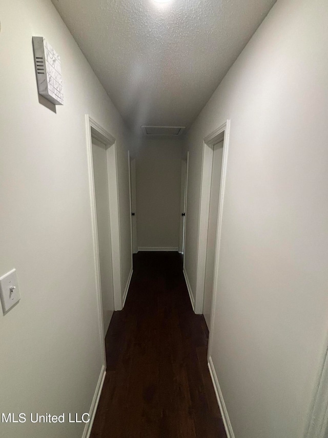 hallway featuring a textured ceiling and dark hardwood / wood-style floors