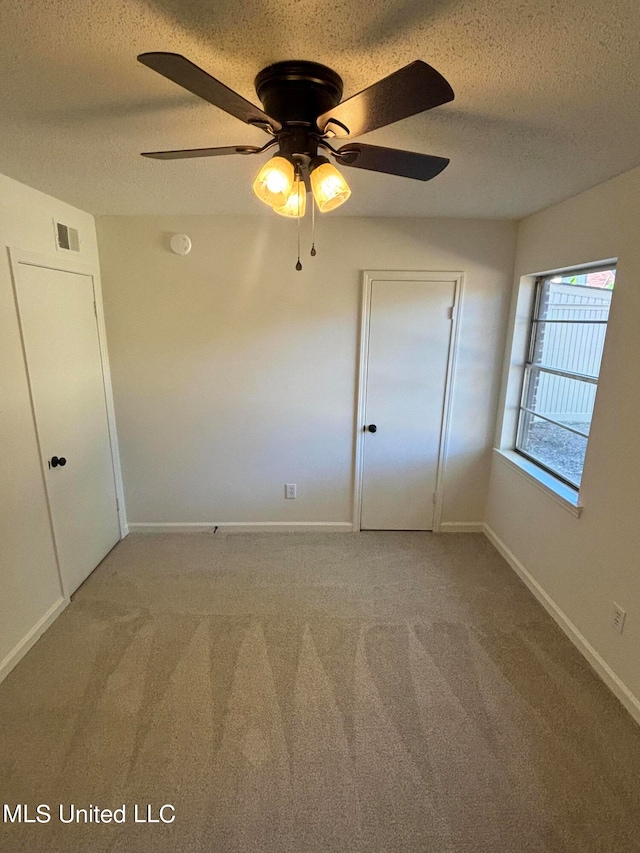 unfurnished bedroom with carpet, a textured ceiling, and ceiling fan