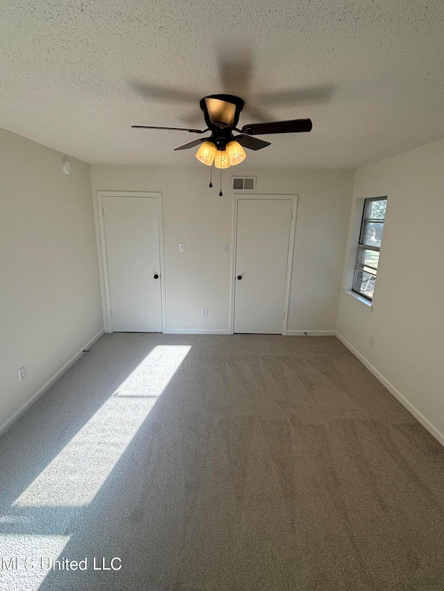 unfurnished bedroom featuring carpet, a textured ceiling, and ceiling fan