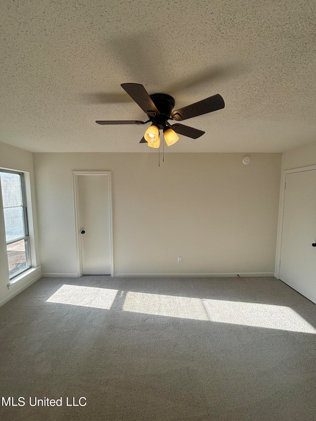 unfurnished room featuring a textured ceiling, carpet, and ceiling fan