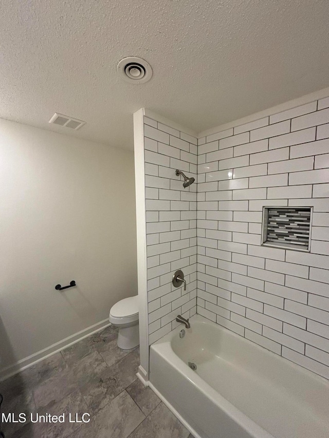 bathroom with tiled shower / bath combo, a textured ceiling, and toilet