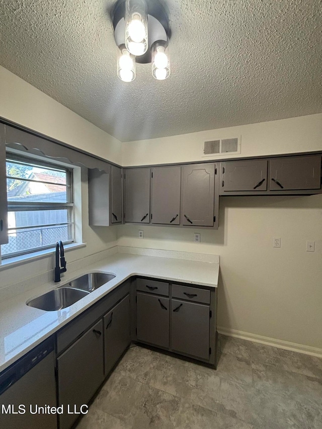 kitchen featuring a textured ceiling, stainless steel dishwasher, sink, and gray cabinetry