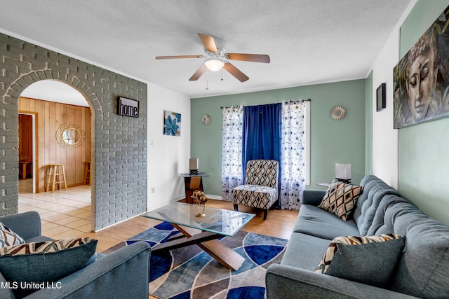 5608 Claresholm Dr, Gautier, MS 39553 - living area featuring arched walkways, a ceiling fan, an accent wall, wood finished floors, and a textured ceiling