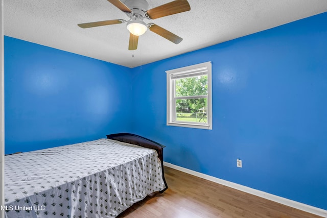 5608 Claresholm Dr, Gautier, MS 39553 - bedroom featuring wood finished floors, a textured ceiling, baseboards, and ceiling fan