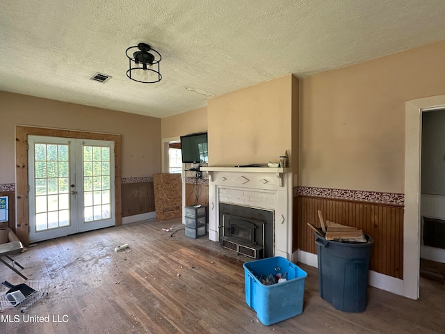 living room featuring hardwood / wood-style floors, a textured ceiling, french doors, and wooden walls