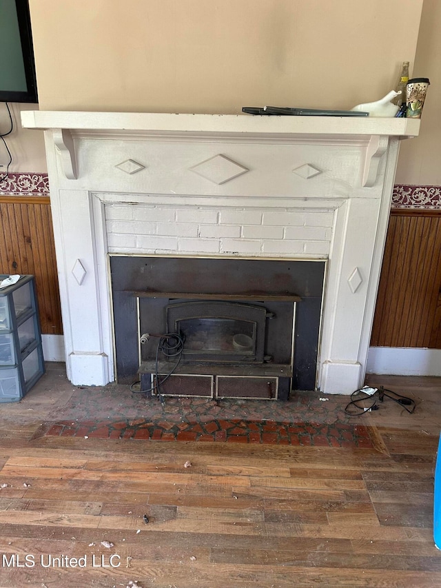 details featuring wood walls, wood-type flooring, and a brick fireplace