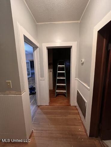 hallway with hardwood / wood-style floors and a textured ceiling