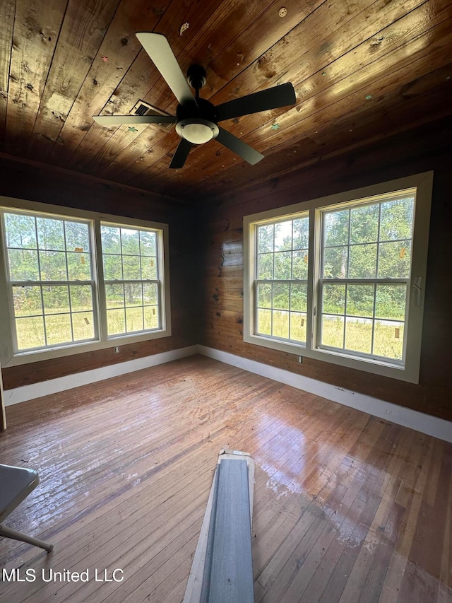 empty room featuring light hardwood / wood-style floors, wood walls, wood ceiling, and ceiling fan