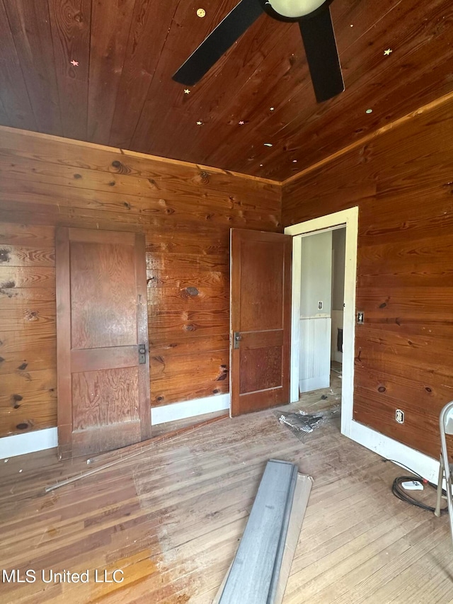 exercise room featuring wooden walls, ceiling fan, hardwood / wood-style flooring, and wooden ceiling