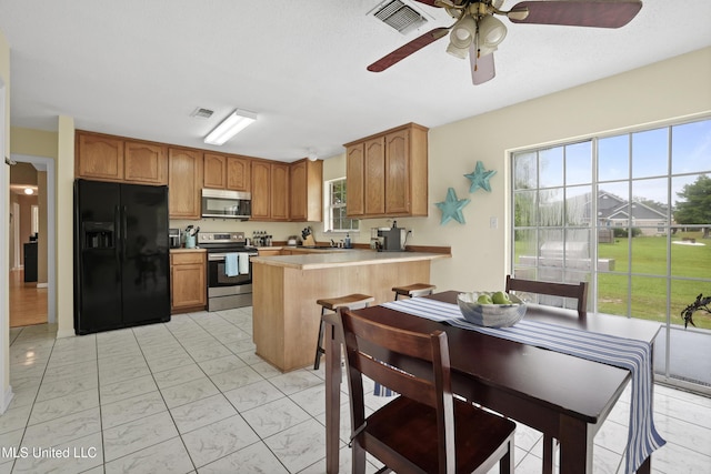 kitchen with stainless steel appliances, light marble finish flooring, a peninsula, and plenty of natural light