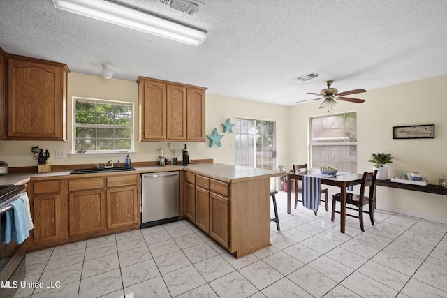 kitchen featuring stainless steel appliances, light marble finish flooring, a peninsula, a sink, and brown cabinetry