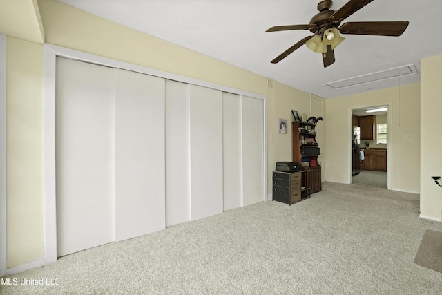 living area featuring a ceiling fan, carpet, and attic access