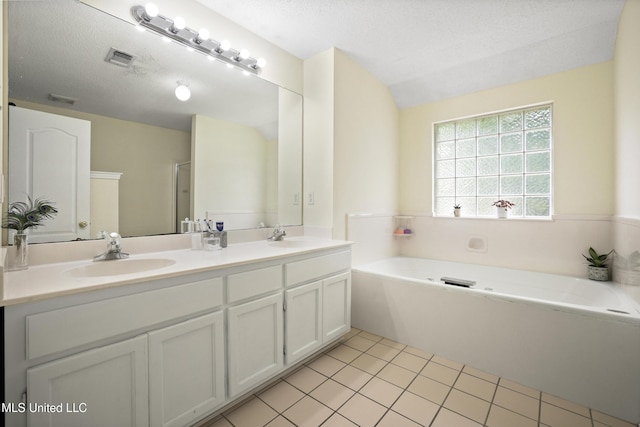 bathroom with double vanity, a bath, tile patterned floors, and a textured ceiling