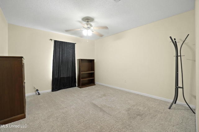empty room with carpet flooring, ceiling fan, baseboards, and a textured ceiling