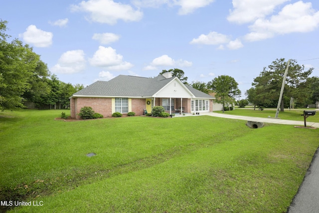 view of front of house with a front lawn, brick siding, driveway, and roof with shingles