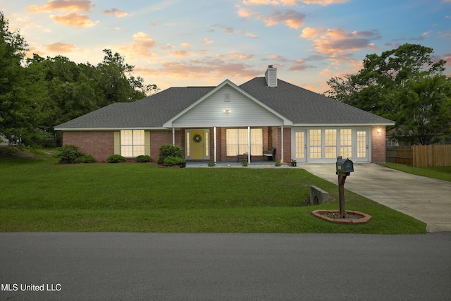 traditional-style home with driveway, brick siding, covered porch, a chimney, and a shingled roof