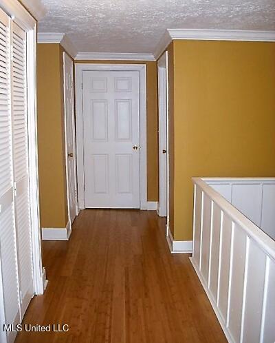 1105 Military Rd, Columbus, MS 39701 - corridor featuring wood finished floors, crown molding, a textured ceiling, and an upstairs landing