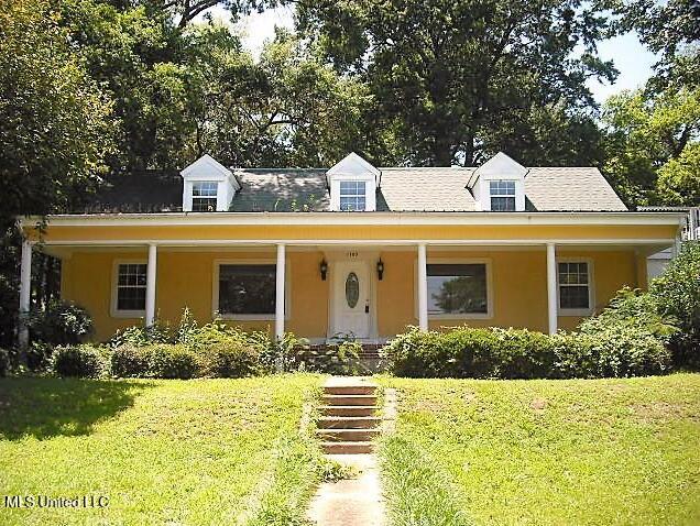 1105 Military Rd, Columbus, MS 39701 - cape cod house featuring a front yard, stucco siding, and a porch