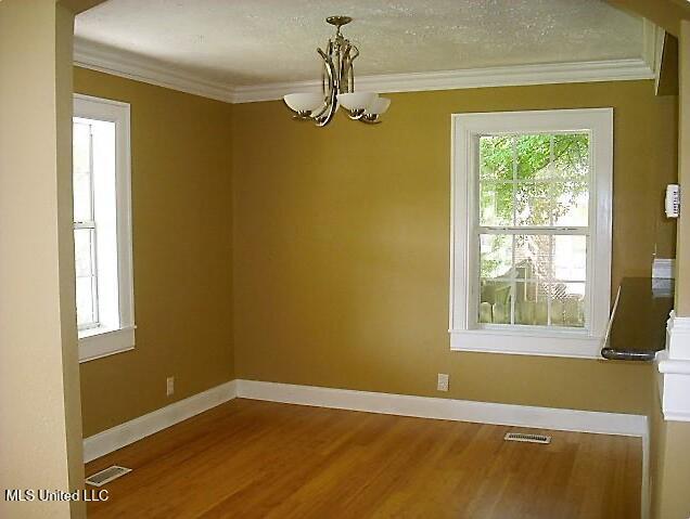 1105 Military Rd, Columbus, MS 39701 - unfurnished room with a chandelier, healthy amount of natural light, crown molding, and wood finished floors