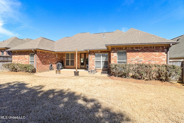 back of house with a patio area, roof with shingles, and brick siding