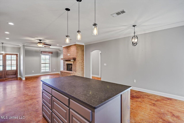 kitchen with pendant lighting, ceiling fan with notable chandelier, ornamental molding, and a fireplace